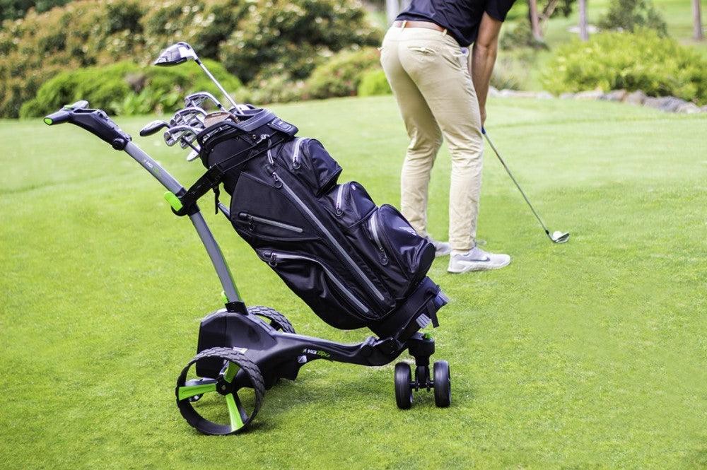 Electric golf buggy with golf bag on grassy course, golfer preparing to putt, Hillside Buggies