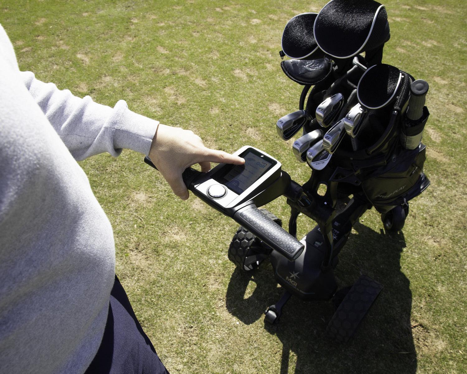 Person operating electric golf buggy with golf clubs and digital control on grass