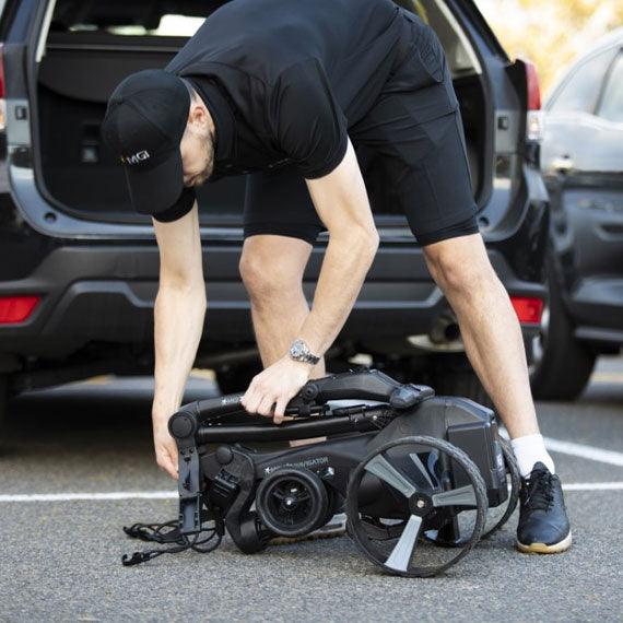 Man loading folded electric golf buggy into car at Hillside Buggies parking lot